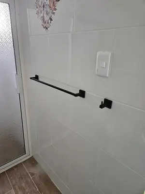 a shower with a white tile wall with a towel rack at Eastern Breeze in Hainamosa