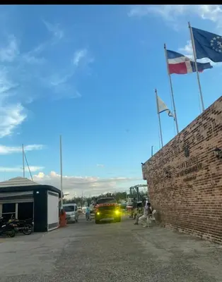 a yellow car parked in a parking lot with two flags at Apartamento de recreación vista al mar in Boca Chica