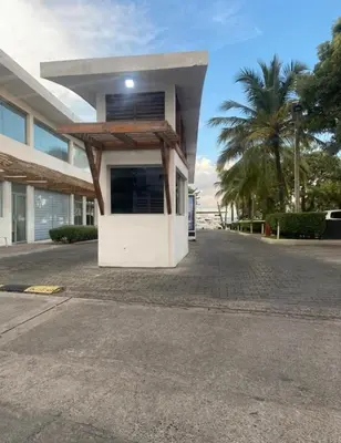 a building on a street with a palm tree at Apartamento de recreación vista al mar in Boca Chica