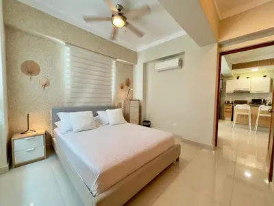 a bedroom with a large bed and a kitchen at Acogedor apartamento ÁGORA MALL in Colorado