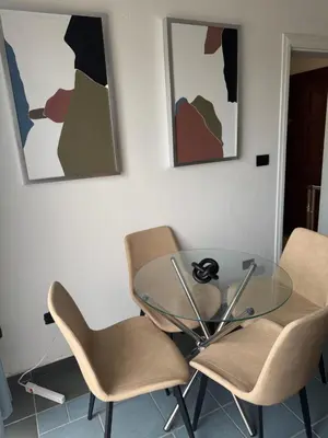 a glass table and chairs in a room with paintings at Costa Lunga-Tropicasa in Boca Chica