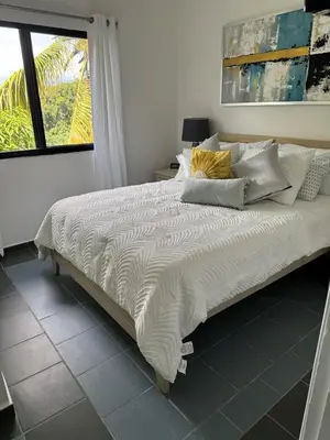 a bedroom with a bed with white sheets and a window at Costa Lunga-Tropicasa in Boca Chica