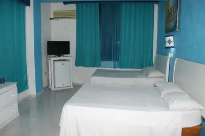 two beds in a room with blue walls and a tv at Aparta Hotel Azzurra in Boca Chica