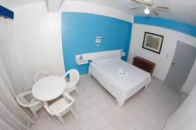 a bedroom with a white bed and a table and chairs at Aparta Hotel Azzurra in Boca Chica