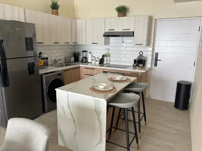 a kitchen with a counter with stools and a refrigerator at Apartment Punta Cana Oasis ONA Residences in Punta Cana