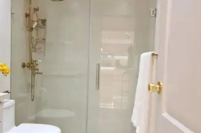 a white bathroom with a shower and a toilet at Stylish 3BR Condo, Full AC, Wi-Fi in Santo Domingo