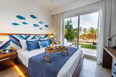 a hotel room with a bed and a large window at Vista Family Garden Suite Pool front 2 Bdrms in Punta Cana