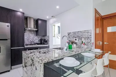 a kitchen with a marble counter top and white chairs at Upscale City Center Condo Pool in Santo Domingo