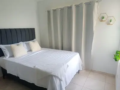 a bedroom with a bed with white sheets and curtains at Apartamento palmera del este 3 in La Javilla