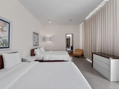 a white hotel room with two beds and a desk at Stay at Ultravioleta Cabarete Beachfront Apartments by EvoKey in Cabarete