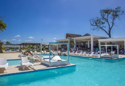 a resort swimming pool with white chairs in the water at Laguna Park Apartments in Sosúa