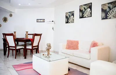 a living room with a white couch and a table at Apartamento en el malecón cerca de la playa in San Felipe de Puerto Plata