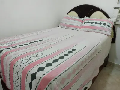 a bed with a pink and black blanket and pillows at Apartaestudio en el malecón y cerca de playas in San Felipe de Puerto Plata