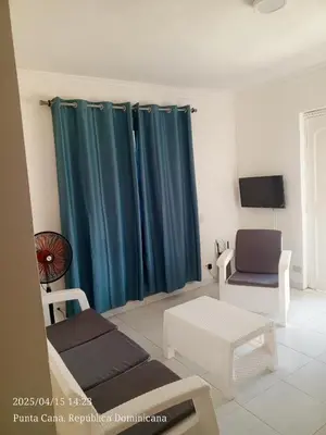 a living room with blue curtains and a chair at Hogar cerca de la playa in Punta Cana