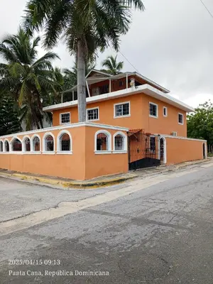 an orange building with a palm tree in front of a street at Hogar cerca de la playa in Punta Cana