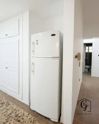 a white refrigerator in a kitchen next to a door at Tu refugio en Los Corales Punta Cana, wifi rápido y piscina in Punta Cana