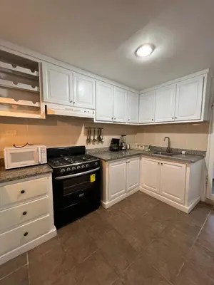 a kitchen with white cabinets and a black stove at Tu refugio en Los Corales Punta Cana, wifi rápido y piscina in Punta Cana