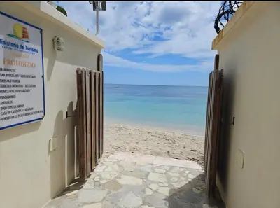 a door to the beach with the ocean behind it at Family Friendly Beach Apartment in Juan Dolio in Los Corrales