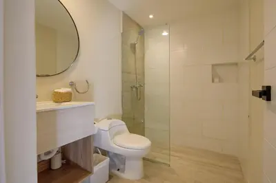 a bathroom with a toilet and a glass shower at Ático ONA White Sands | Terraza & Picuzzi privado in Punta Cana