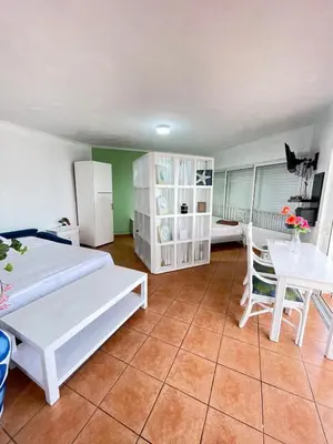 a bedroom with two beds and a table and a refrigerator at comfortable apartment in La Puntica de Juan Dolio
