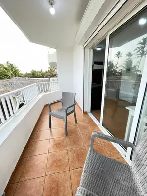 a balcony with a table and a chair on a porch at comfortable apartment in La Puntica de Juan Dolio