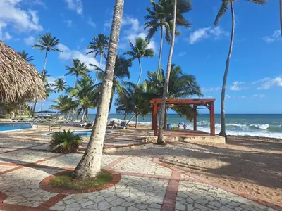 a beach with a pavilion and palm trees and the ocean at marina view in La Puntica de Juan Dolio