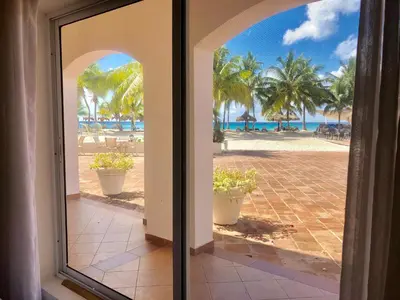 an open door to the beach with palm trees at Cadaques Bayahibe Family Apts in Bayahibe