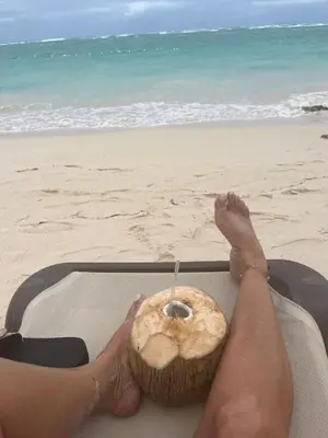 a person with a coconut in their lap on the beach at Beautiful 2 bedroom apartment on the beach in Punta Cana