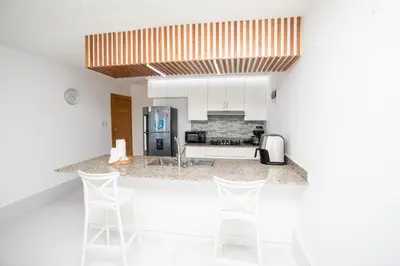 a kitchen with a counter with four white bar stools at Apartment with Pool, Cofresi in San Felipe de Puerto Plata