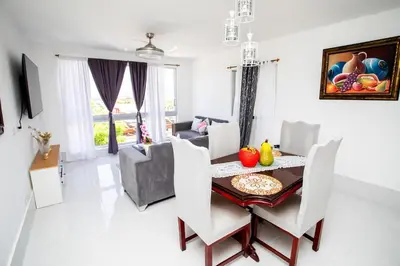 a dining room and living room with a table and chairs at Apartment with Pool, Cofresi in San Felipe de Puerto Plata