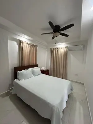 a bedroom with a white bed with a ceiling fan at Cabarete Town House in Cabarete