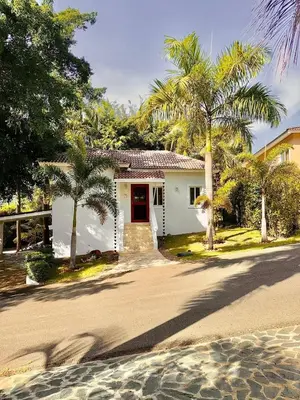 a white house with palm trees in front of a street at Charming 2 bed 2bath villa 77B with private pool in Sosúa