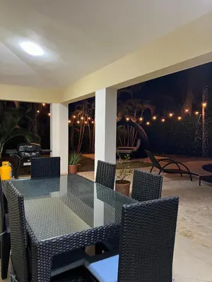 a glass table and chairs on a patio at night at Villa 156, 3 bedrooms and 3 bathrooms with private pool in Sosúa