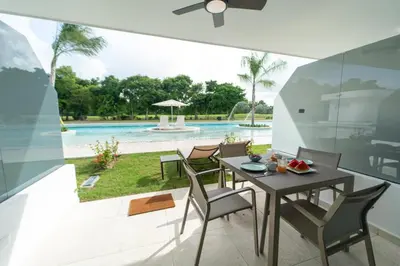 a dining room with a table and chairs and a pool at Aqua Fam Swim out Suite - Pool @ Cana Rock G 117 in Punta Cana