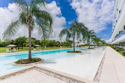 a swimming pool with palm trees in a building at Aqua Luxe @ Cana Rock terrace to pool access E-105 in Punta Cana