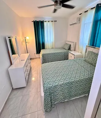 a small bedroom with two beds and a mirror at Cozy 2 Bedroom Apartment Boca Chica in Boca Chica