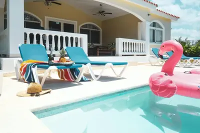 a swimming pool with two chairs and a pink flamingo at 4-Suite Tranquil Retreat in Sosua Ocean Village in Sosúa