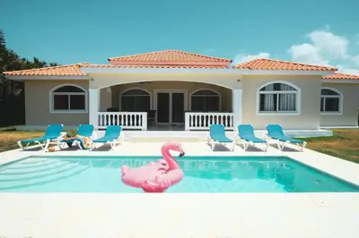 a pink flamingo in a swimming pool in front of a house at 4-Suite Tranquil Retreat in Sosua Ocean Village in Sosúa