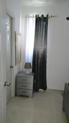 a room with a curtain and a table with a lamp at 4 vecinos in Santiago de los Caballeros