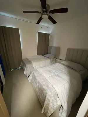 two beds in a bedroom with a ceiling fan at Romana Residence Vacationing Apartment in Cumayasa Kilómetros Diez