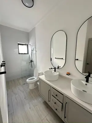 a bathroom with two sinks and a toilet and mirrors at Boho Villa in Oceanfront Comm Sosua Ocean Village in Sosúa