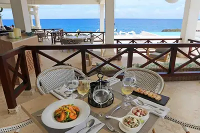a table with a plate of food and glasses of wine at Villa Solana in Oceanfront Com Sosua Ocean Village in Sosúa