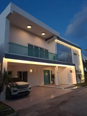 a white house with a car parked in front of it at Modern Villa in Oceanfront Sosua Ocean Village in Sosúa