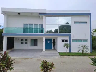 a white house with a blue door at Modern Villa in Oceanfront Sosua Ocean Village in Sosúa