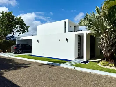 a white house with a car parked in the driveway at Marisol Villa in Oceanfront Comm in Sosúa