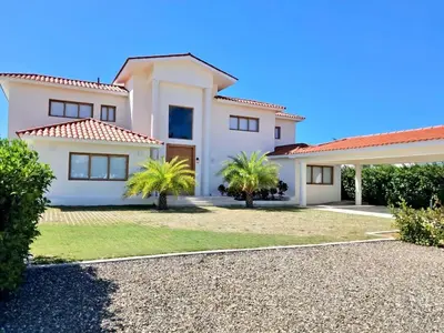 a white house with palm trees in front of it at Villa Caracol in Sosua Ocean Village Santa Fe in Sosúa