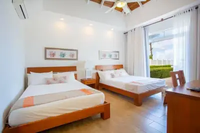 a bedroom with two beds and a desk and a window at Ocean Haven Oceanfront in Sosua Ocean Village in Sosúa