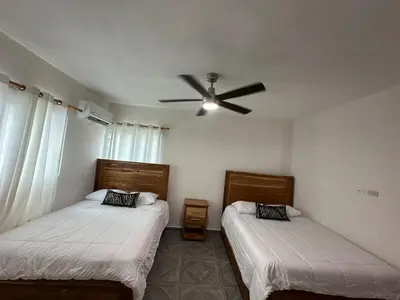 two beds in a room with a ceiling fan at Villa kiyana-14 pax, 5min de la playa en Las Galeras in Las Galeras