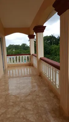 a balcony with columns and a view of trees at Apartamentos Nuevo Amanecer in Río San Juan