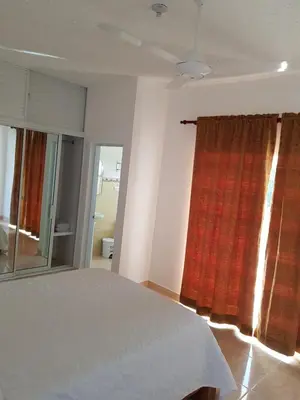 a bedroom with a bed and a red curtain at Apartamentos Nuevo Amanecer in Río San Juan